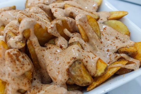 Close up of patatas bravas, typical Spanish dish with spicy sauce.