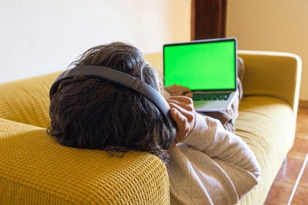 Relaxed Man Sitting On Sofa At Home With Headphones And Laptopの写真素材