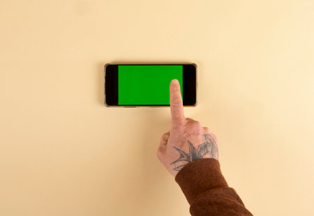 hands using mobile phone with green screen isolated on a pastel colored backgroundの写真素材