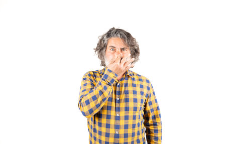 Bearded man in checkered shirt smelling something smelly and disgusting holding his breath with fingers in his nose, bad smellの写真素材