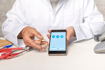 Audiologist showing smartphone application to make adjustments. Manage hearing aid settings via mobile appの写真素材
