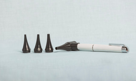 Pocket otoscope with multiple specula for ear examination lying on light blue medical table