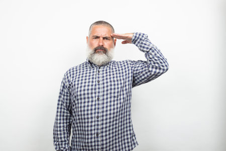 Portrait of a serious mature man with gray hair and beard giving a saluteの写真素材