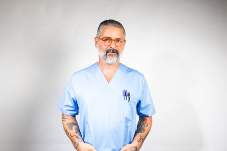 Experienced male nurse standing confidently with hands in pockets, showing professionalism and healthcare expertiseの写真素材