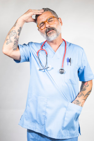 Tired doctor feeling a strong headache, eyes closed and touching his foreheadの写真素材