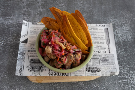 Picarones with thinly sliced red onions, served with fried plantain chipsの写真素材