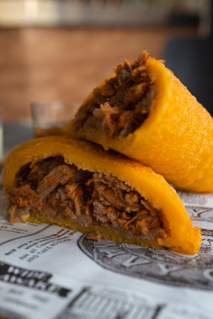 Savory fried empanada filled with traditional pulled pork served on patterned paperの写真素材