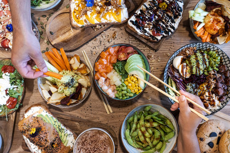 Overhead view of hands sharing a table full of healthy and colorful foodの写真素材