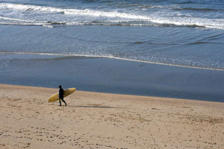 Surfer at the beach and oil platform in the ocean