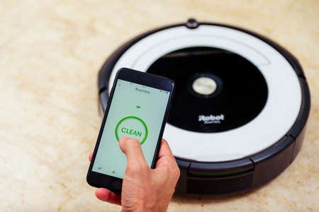 Berlin, Germany, August 29, 2019. Man hand activating the roomba irobot vacuum cleaner from the...