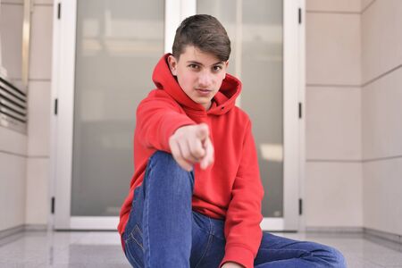teenager with red clothes pointing his index fingerの写真素材
