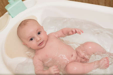 Cute baby having bath in white tubの写真素材