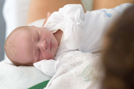 new born infant asleep in the blanket in delivery room