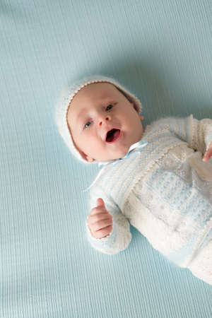 happy and smiling baby wearing blue and white suit on blue backgroundの写真素材