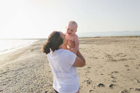 Mother and daughter running on the beach at sunset time during summer vacation. Family people having fun together outdoor. Travel and happiness lifestyleの写真素材