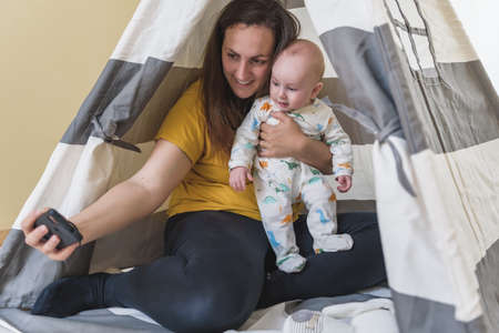 woman with her baby taking a picture while playing. family time