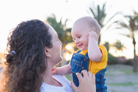 mother and daughter walking near forest by the road in the wheat field on sunsetの写真素材