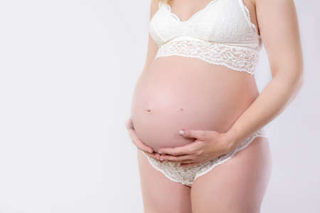Pregnant belly with red ribbon. Nine month. Third trimester