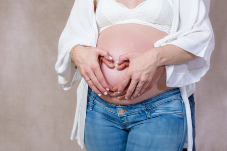 Pregnant belly with red ribbon. Nine month. Third trimesterの写真素材