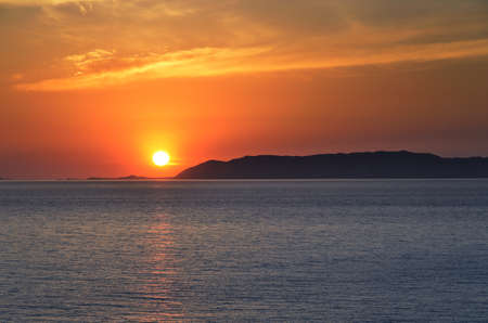 Hermosa puesta de sol cerca de la playa de Ampeli, Folegandros  Al fondo el sol se pone sobre la isla de Milos の写真素材