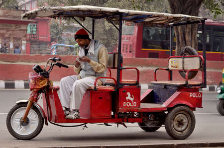 DELHI, INDIA - FEB 8, 2014  A autorickshaw driver is waiting costumers in a street of Delhi 