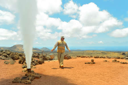 Lanzarote  Canary Islands , Spain - May 5, 2012  An employee who works in the National Park of Timanfaya causes a geyser, when a bucket of water is emptying in a hole in the ground  のeditorial素材