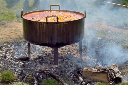 Cooking in the countryside with firewood, a stew of potatoes with meat, in a big cauldron.の写真素材