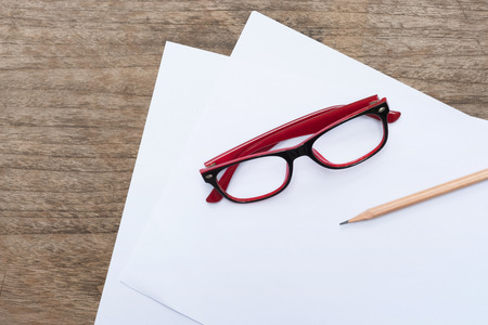 Blank paper with pencil and eye glasses on wood table.の写真素材