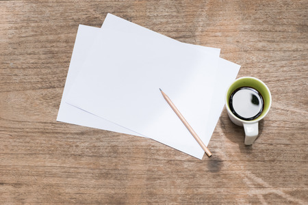 Top view blank paper with pencil and a cup of coffee on wood table.の写真素材