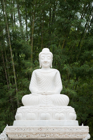 Marble Buddha sculpture under green bamboo forest background.の写真素材