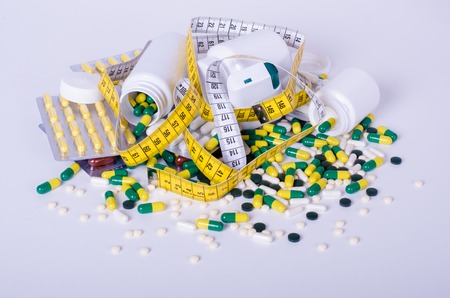 Pills and measuring tape isolated in a white backgroundの写真素材