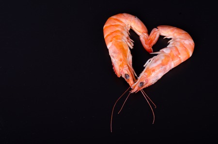Two shrimps forming a heart in a black backgroundの写真素材
