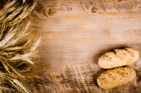 Fresh buns and wheat ears on wooden backgroundの写真素材