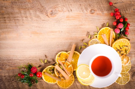 Slices of dried orange, lemon, cinnamon, cloves, cardamom, pine cone and cup of tea. Christmas and New Year decoration. Free space for text.の写真素材