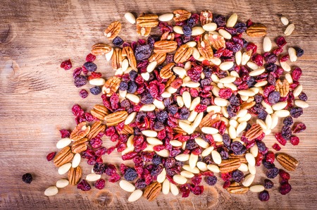 Dried fruits - pecan, cranberry, raisin, almond on wooden background.の写真素材