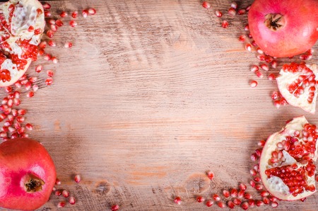 Ripe pomegranate fruit and seeds on wooden background. Eating frame.の写真素材