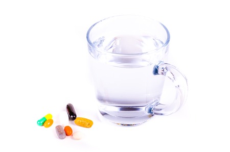 Glass of water and pills on white backgroundの写真素材