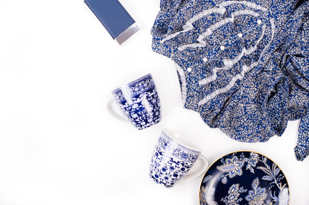 Outfit of stylish ladies clothing on a white background. Blue retro shoes, dress, perfume, plate and cups. Free space for your text.の写真素材