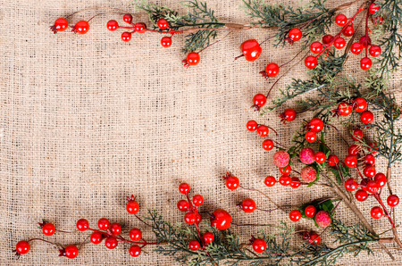 Branch with red berries on canvas, sackcloth background. Christmas and New Year decoration. Free space for textの写真素材