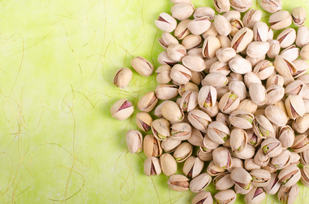 Salt pistachios on green background. Free space for your text.の写真素材