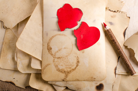 Stack old papers, notebook, wooden pencil and two vintage red hearts on burlap, sackcloth background. Retro design effects.の写真素材