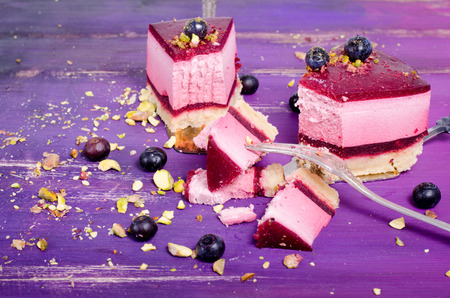 Piece of delicious raspberry cake with fresh raspberries, blueberry, currants and pistachios on...