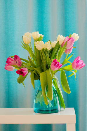 Bouquet of beautiful pink and yellow tulips in tiffany vase. Free space for your text.の写真素材