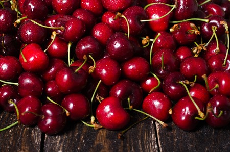 Cherry background. Fresh juicy cherries on wooden background, top view. Free space for your text.の写真素材