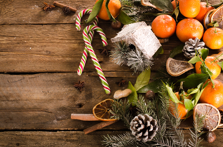 Christmas background - vintage wood, candy cane, house, cinnamon, star anise, sweet mandarins. Top view, blank spaceの写真素材