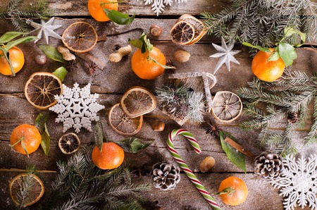 Magic Christmas background - vintage wood, candy cane, house, cinnamon, star anise, sweet mandarins with green leaves, cones, snowflakes. New Year. Top view, blank spaceの写真素材
