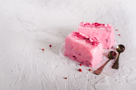Pink cakes and two teaspoons for mother, woman or girlfriend on white concrete background. Free space for your text.の写真素材
