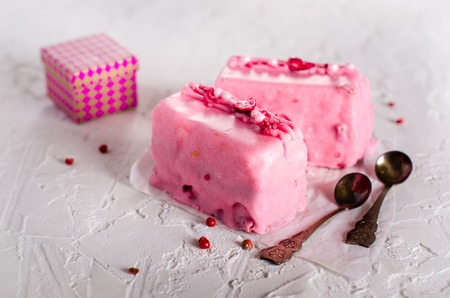 Valentine pink cakes and two teaspoons on white concrete background. Free space for your text.の写真素材