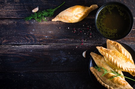 Kibinai, kybyn, kybynar, chiburekki - traditional pastries filled with mutton on dark wooden background. Lithuania. Free space for your textの写真素材