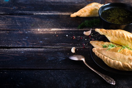 Kibinai, kybyn, kybynar, chiburekki - traditional pastries filled with mutton on dark wooden background. Lithuania. Free space for your textの写真素材